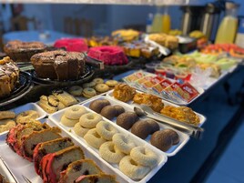 Un bufé con diversas opciones de panadería, incluyendo pasteles, galletas y bollos.