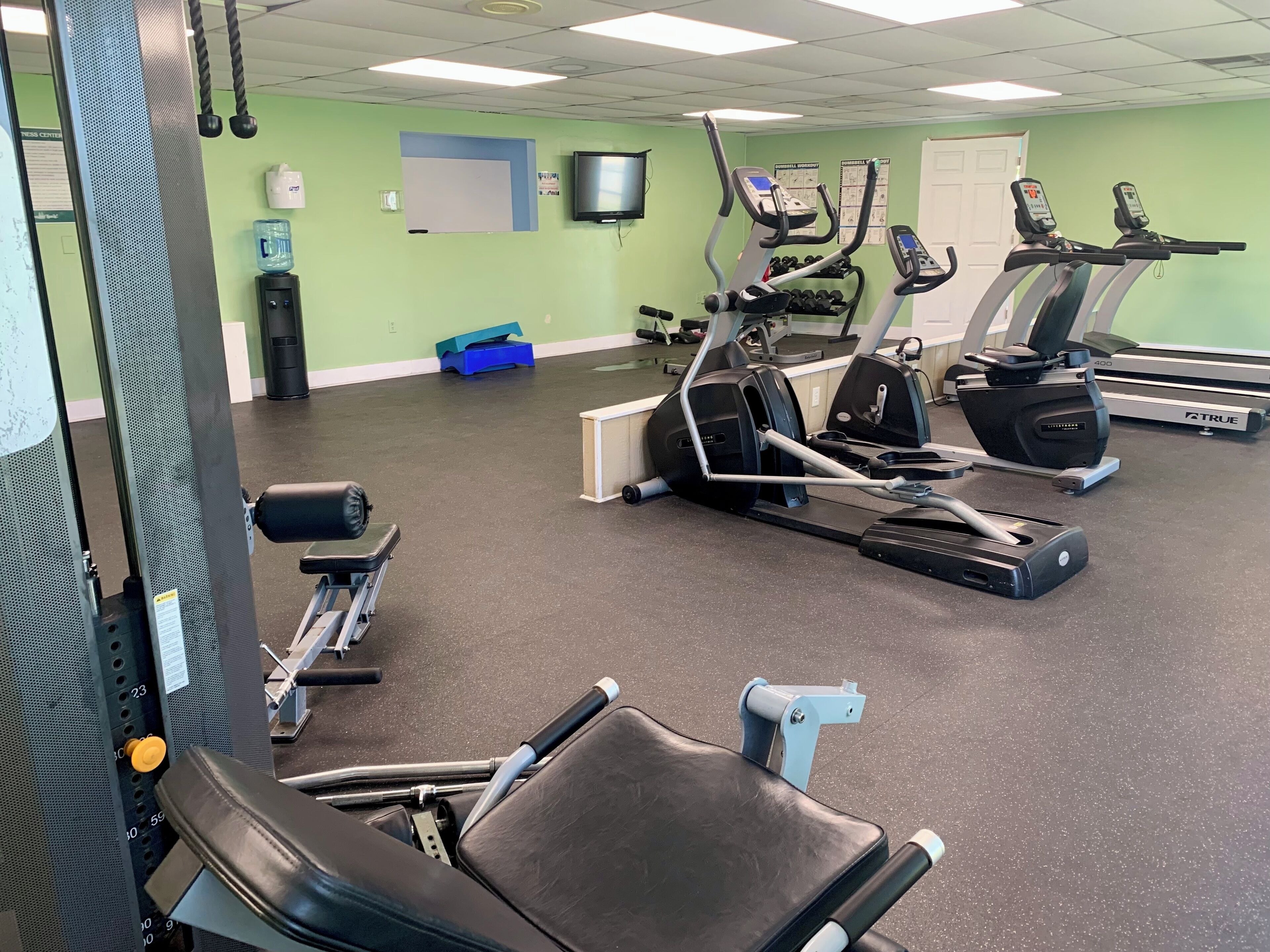 Ein Fitnessstudio mit Laufbändern, Crosstrainern und Gewichten.