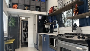 Een moderne keuken met een inbouwfornuis, roestvrijstalen apparatuur en diverse decoratieve objecten op planken.