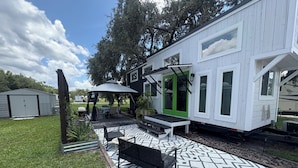 Een stacaravan met een terras, een vloer met een patroon, tuinmeubilair en een groene deur.