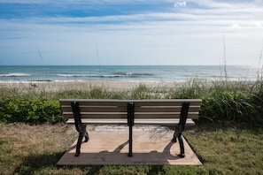 A wooden bench with metal armrests facing the ocean. - Off Season - Steep DIscount - Heated Pool (Indialantic)