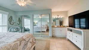 A bedroom with a bed, a ceiling fan, a large mirror, a TV, and a sliding door leading to another room. - Off Season - Steep DIscount - Heated Pool (Indialantic)