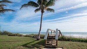 A beachside area with a wooden staircase leading to a viewing platform, a bench, and a palm tree. - Off Season - Steep DIscount - Heated Pool (Indialantic)