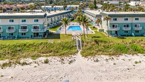 A beachfront hotel with multiple-story buildings, a swimming pool, and a sandy beach path leading to the pool. - Off Season - Steep DIscount - Heated Pool (Indialantic)