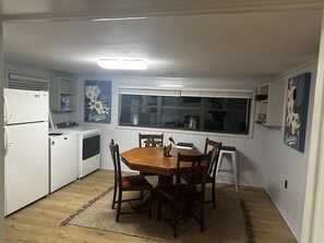 Eine kleine Küche mit weißen Geräten, einem Holzespeisetisch und einem großen Fenster.