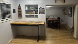 A dining area with a wooden table and chairs, a small shelf with decorative items, and a sign that reads "The best days are spent fishing." - Quiet Lakefront Cottage (Zwolle)