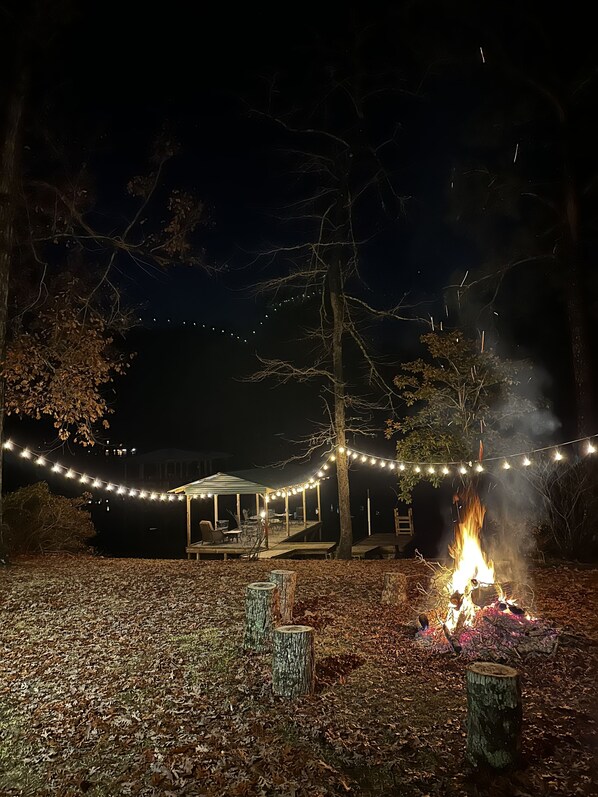 A covered outdoor seating area with string lights and a campfire. - Quiet Lakefront Cottage (Zwolle)