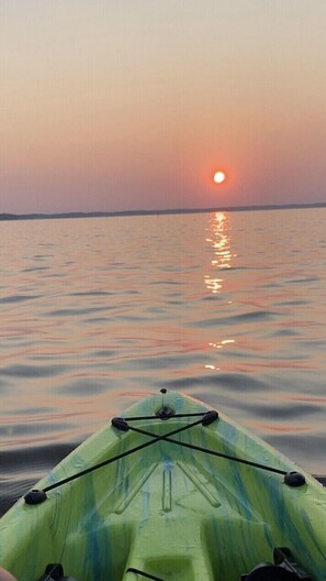 A kayak on calm water with a sunset in the background. - Quiet Lakefront Cottage (Zwolle)