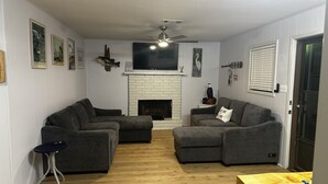A living room with two grey sofas, a small side table, a wooden coffee table, a fireplace, and a mounted TV. - Quiet Lakefront Cottage (Zwolle)