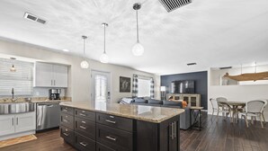 Una cocina moderna con armarios oscuros, encimeras de granito e iluminación colgante.