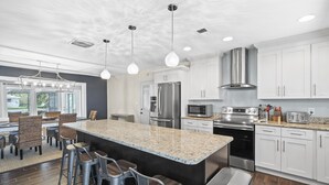 Una cocina moderna con una isla de granito, electrodomésticos de acero inoxidable y armarios blancos.
