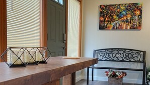 A wooden dining area with a bench and stools, a painting on the wall, and a door with a window.