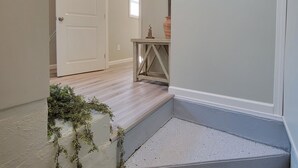 A staircase with a concrete finish, a wooden door, and a small table with a vase and a statue.