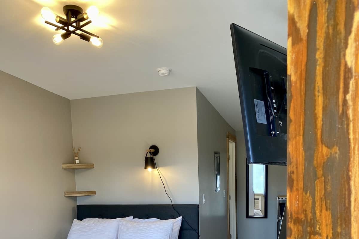 A bedroom with a bed, bedside lamp, and a ceiling light fixture.