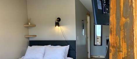 Et soveværelse med seng, sengetøj og en loftlampe.