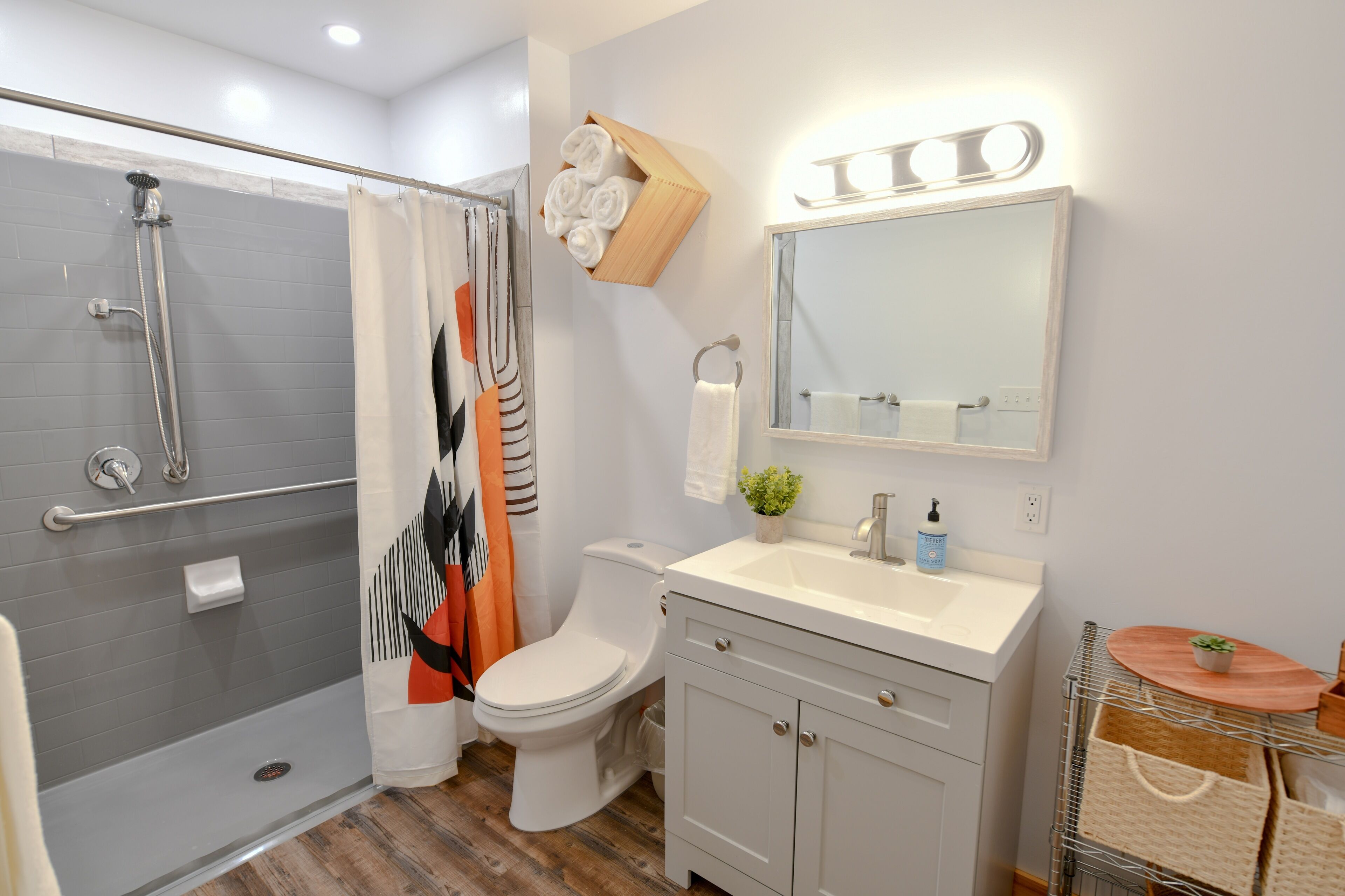 A modern bathroom with a walk-in shower, a toilet, and a vanity with a mirror and sink.