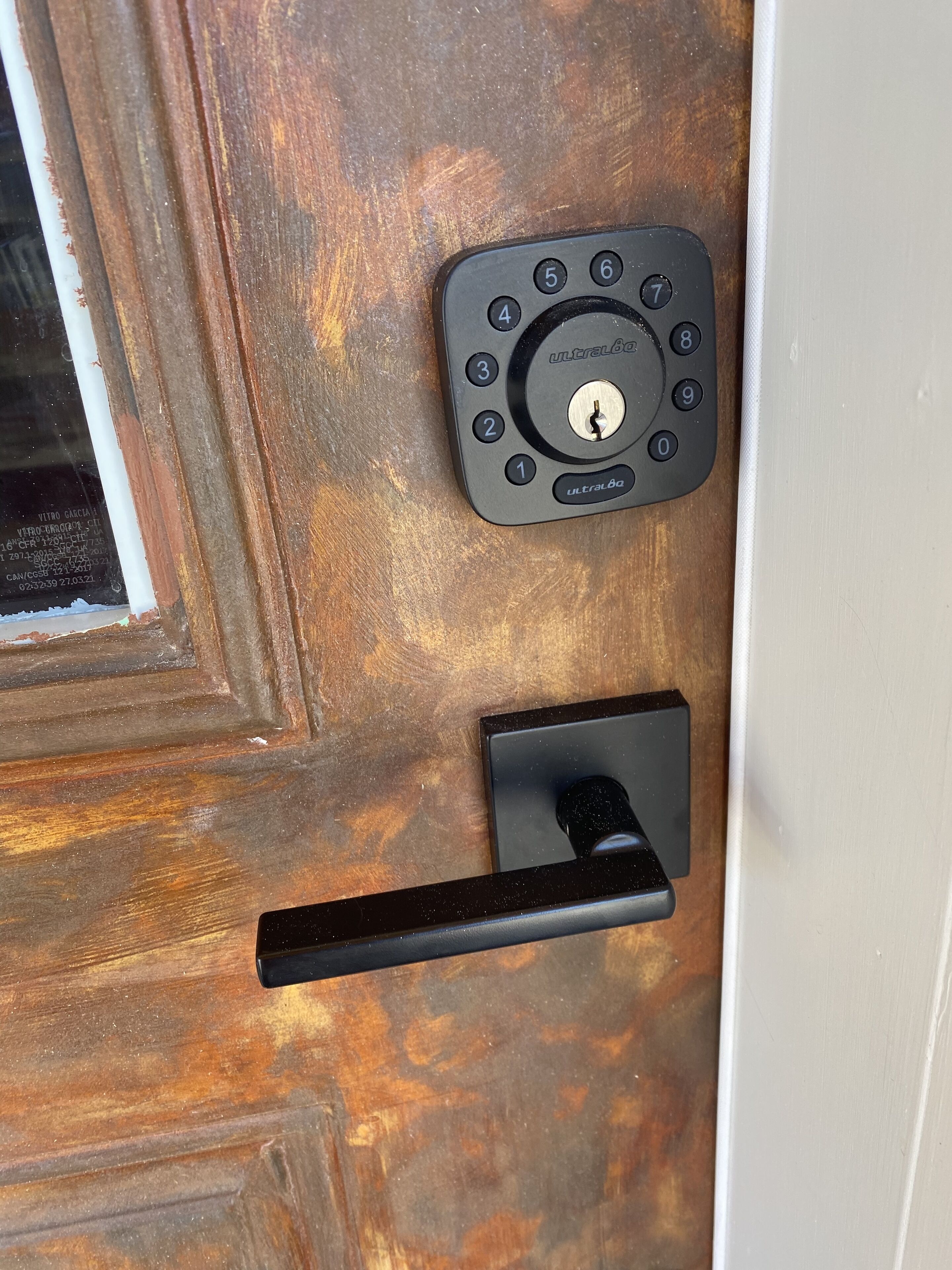 Puerta de madera con cerradura electrónica y picaporte negro.