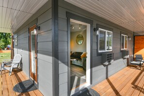 A covered deck with outdoor seating, a door leading to an interior room, and a view of the backyard. - The Darmont Hotel and Suites (Darby)