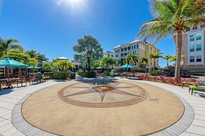 A courtyard with a central circular design, palm trees, and outdoor seating.