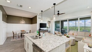 A spacious kitchen with granite countertops, a dining area, and a living room with a large window offering a view. - Harbor Isle Fir, penthouse with views (Bradenton)