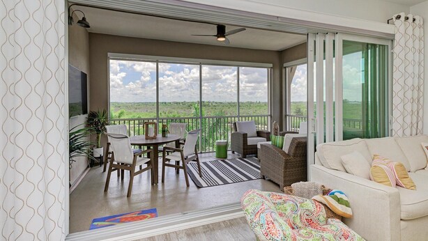 A spacious balcony with a dining area, a sofa, and a TV. - Harbor Isle Fir, penthouse with views (Bradenton)