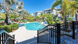 A pool area with palm trees, lounge chairs, and a clear blue sky. - Harbor Isle Fir, penthouse with views (Bradenton)