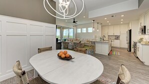 A spacious kitchen with white cabinets, a central island, and a dining area with a round table and chairs. - Harbor Isle Fir, penthouse with views (Bradenton)
