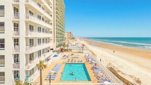 A hotel with a pool area, beach access, and multiple balconies.