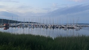 A marina with numerous boats docked, calm water, and a grassy foreground.