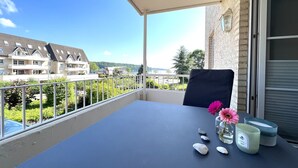 A balcony with a table, a chair, a vase with flowers, and a candle.