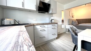 A modern kitchen with white cabinets, a built-in stove, and a coffee machine.