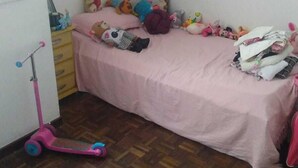 Una camera da letto con un letto rosa, uno scooter e diversi peluche.