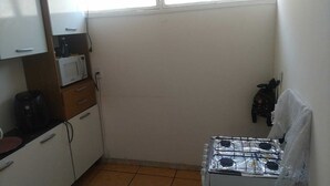Una piccola cucina con mobili bianchi, un forno a microonde, una macchina da caffè e un piano cottura a gas.