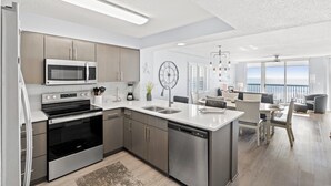 A modern kitchen with stainless steel appliances, a dishwasher, and a large island with a sink. - Ashworth 309-Oceanfront 4BR Near Main Street, Pool (North Myrtle Beach)