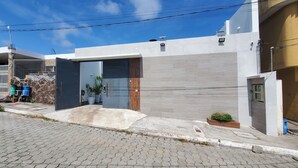 Un moderno edificio residencial con garaje, plantas en macetas y entrada pavimentada.