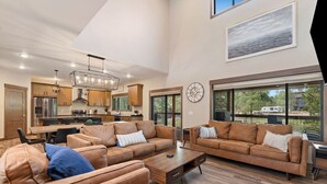 A spacious living area with leather sofas, a wooden coffee table, and a kitchen in the background. - The Fireside-Hot Tub, Firepit, Fireplace (Lead)