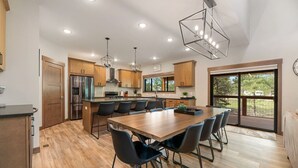 A modern kitchen with wooden cabinets, a central island, and a dining area with chairs. - The Fireside-Hot Tub, Firepit, Fireplace (Lead)