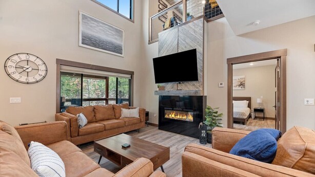 A spacious living room with a fireplace, leather sofas, a coffee table, and a large clock on the wall. - The Fireside-Hot Tub, Firepit, Fireplace (Lead)