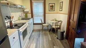 Una cocina compacta con estufa, lavamanos y comedor con mesa y sillas.