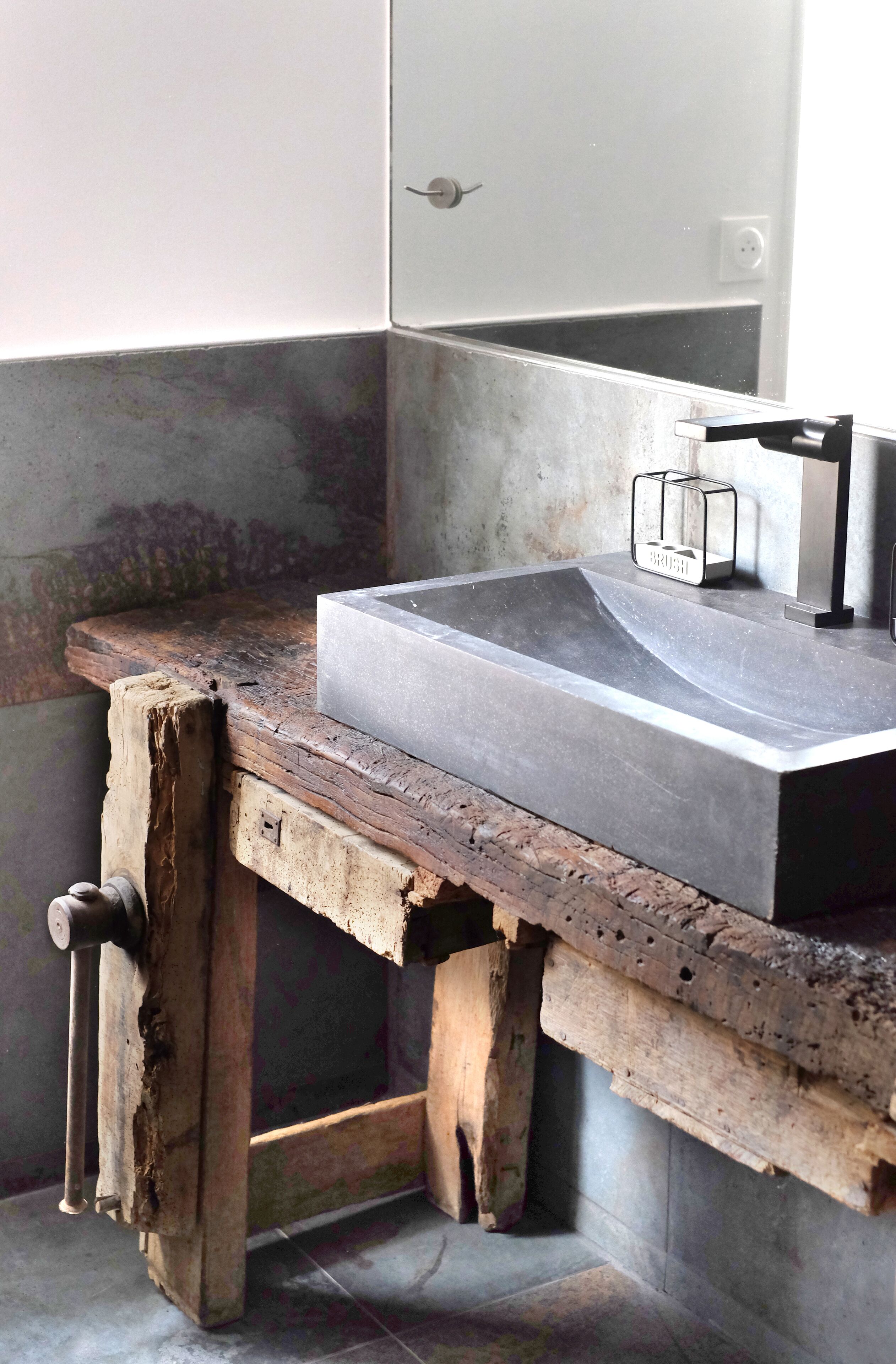 A bathroom with a rustic wooden bench, a modern sink, and a towel rack.