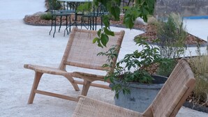 Two wicker lounge chairs with metal frames, positioned on a gravel surface, surrounded by greenery and a concrete planter with plants. - Design cottage in Drome Provençale (Vinsobres)