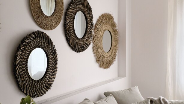 A living room with a beige sofa, a potted plant, and four wall-mounted mirrors with woven frames. - Design cottage in Drome Provençale (Vinsobres)