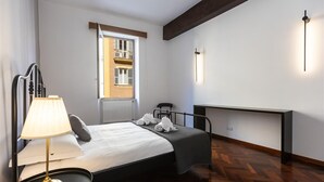A hotel room with a bed, bedside table, lamp, and a view of a balcony.