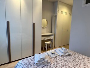 A bedroom with a bed, a bedside table, a mirror, and a wardrobe.