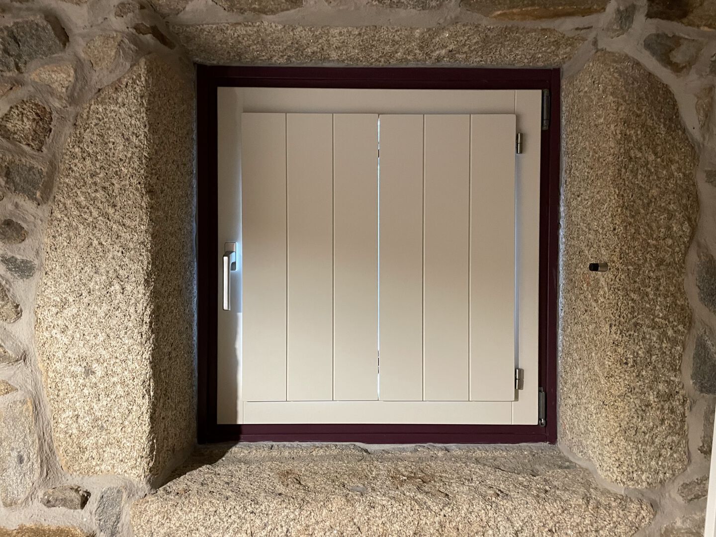 A stone-framed door with a simple design, set in a room with stone walls.