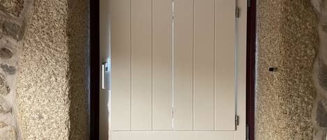 A stone-framed door with a simple design, set in a room with stone walls.