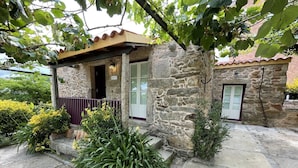 Un bâtiment en pierre doté d’un petit porche, d’une porte et d’une fenêtre.