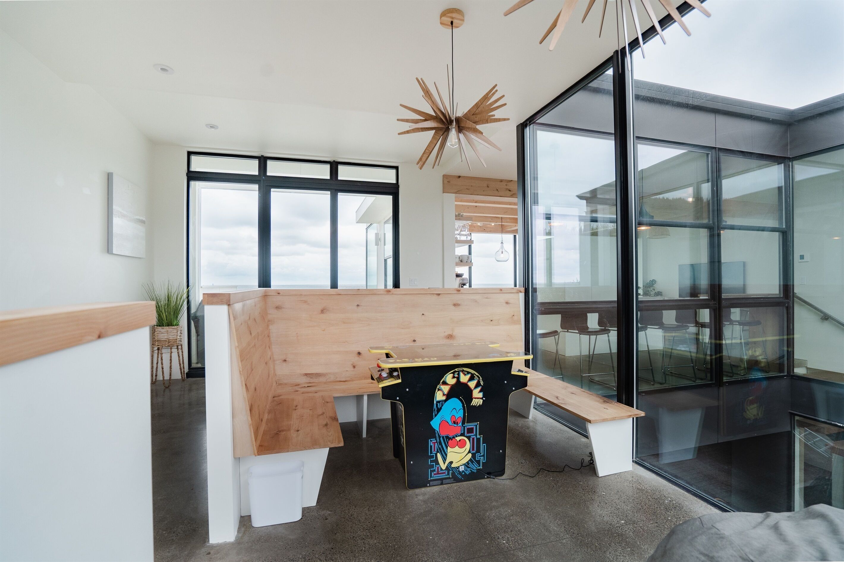 Un intérieur moderne avec un banc en bois, une œuvre d’art colorée et de grandes fenêtres offrant une vue dégagée.