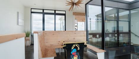 Un intérieur moderne avec un banc en bois, une œuvre d’art colorée et de grandes fenêtres offrant une vue dégagée.