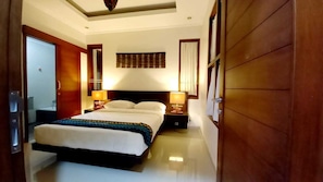 A hotel room with a large bed, two bedside tables with lamps, a wooden wardrobe, and a ceiling fan. - Villa 3 bedroom Umah Kita D' Jimbaran (Jimbaran)